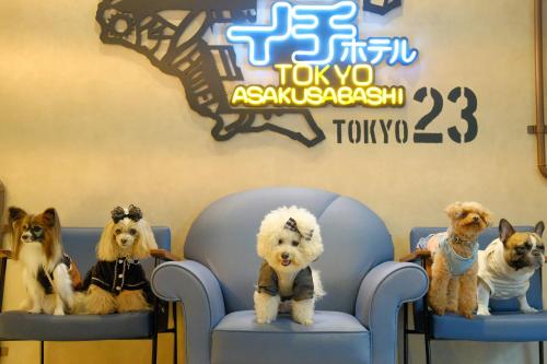 quattro cani seduti sulle sedie di fronte a un cartello di ICI HOTEL Asakusabashi a Tokyo