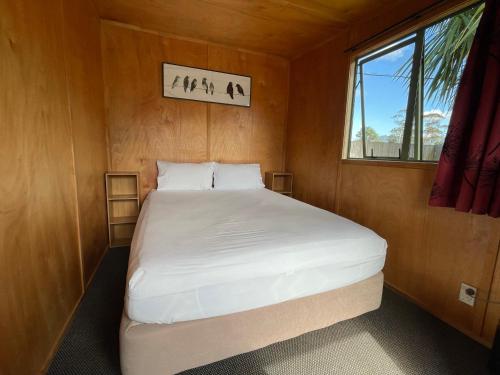 a bed in a small room with a window at Athenree Hot Springs & Holiday Park in Waihi Beach