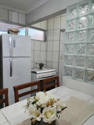a kitchen with a white refrigerator and a table with flowers at Praia do Tombo in Guarujá