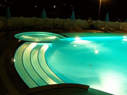 a swimming pool at night with lights in it at Ninos On The Beach Hotel in Roda