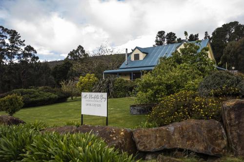a house with a sign in front of a yard at Little Norfolk Bay Events and Chalets in Taranna