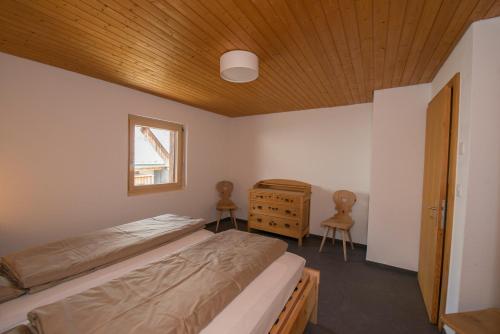 a bedroom with two beds and a wooden ceiling at Chasa Tablà Guarda in Guarda