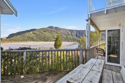 a porch with a wooden bench and a view of a river at Millard House - Marlborough Sounds in Grove