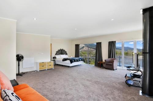 a large bedroom with a bed and a balcony at Millard House - Marlborough Sounds in Grove