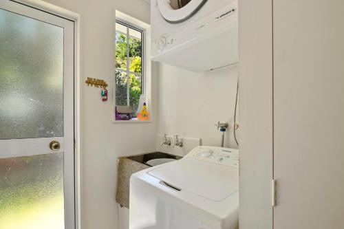 a white bathroom with a sink and a window at Millard House - Marlborough Sounds in Grove