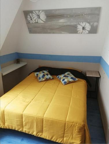 - une chambre avec un lit jaune et 2 oreillers dans l'établissement Appartement à 50 m de la plage avec WIFI, à Villers-sur-Mer