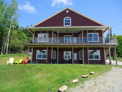 a red house with a deck and chairs on the lawn at The Fiddle and the Sea Bed and Breakfast in Port Hood