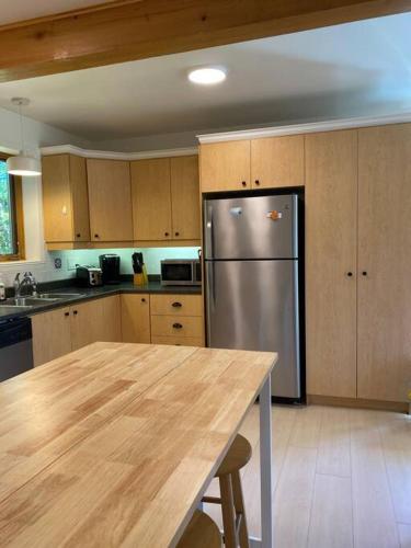 a kitchen with a stainless steel refrigerator and wooden cabinets at Chalet «L'Autrichien» de Charlevoix in Petite-Rivière-Saint-François