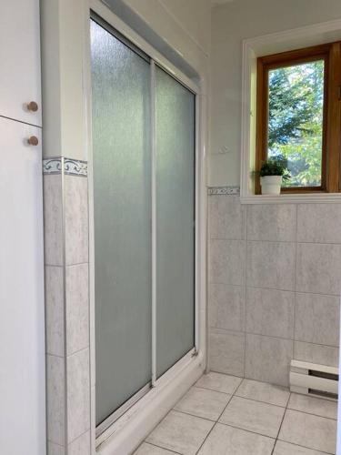 a bathroom with a glass shower with a window at Chalet «L'Autrichien» de Charlevoix in Petite-Rivière-Saint-François