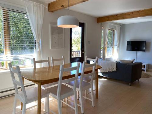 a dining room and living room with a table and chairs at Chalet «L'Autrichien» de Charlevoix in Petite-Rivière-Saint-François