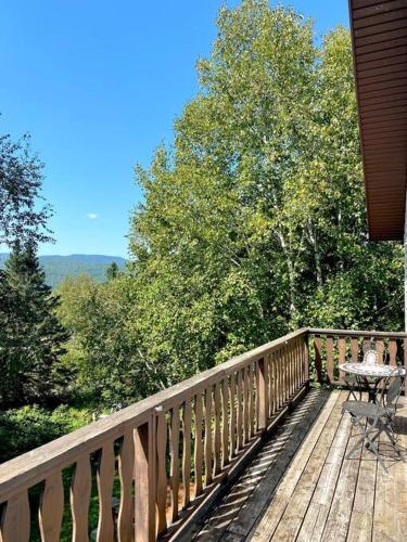 a wooden deck with a table and a table on it at Chalet «L'Autrichien» de Charlevoix in Petite-Rivière-Saint-François
