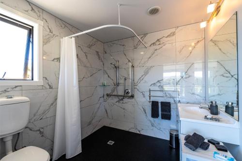uma casa de banho com um chuveiro, um lavatório e um WC. em Inverlair Lodge em Oturehua