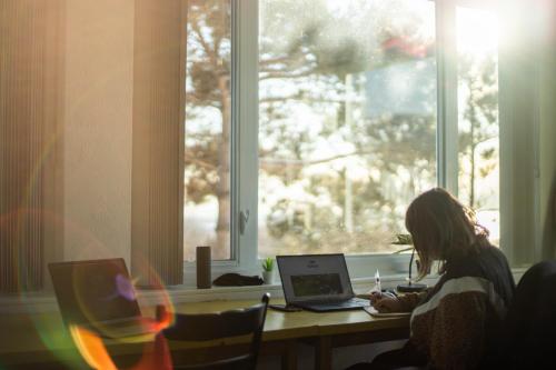 a woman sitting at a desk with a laptop computer at Auberge de nos Aieux in Les Éboulements
