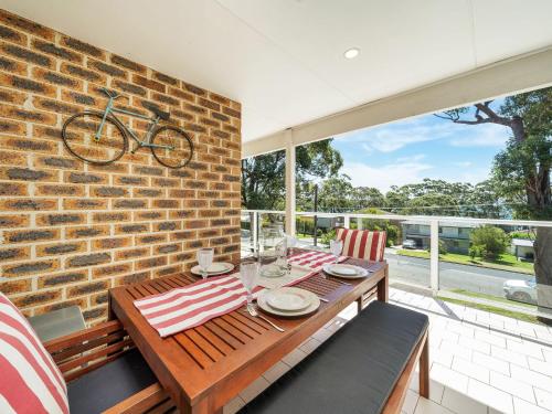 a dining room with a table and a brick wall at Kalimna by Experience Jervis Bay in Vincentia