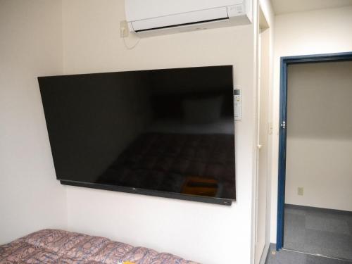 a large flat screen tv hanging on a wall at Station Business Hotel Tenshukaku in Hitoyoshi
