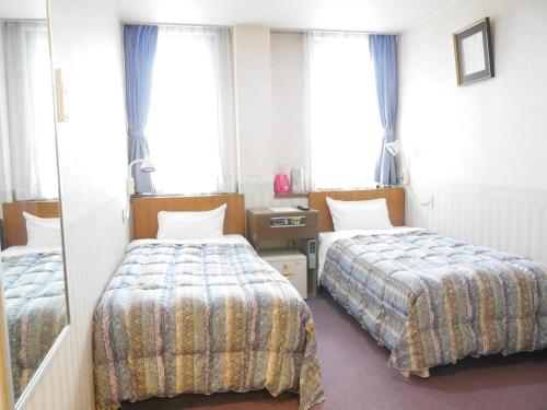 a hotel room with two beds and a mirror at Station Business Hotel Tenshukaku in Hitoyoshi