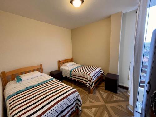 two beds in a small room with a window at Apartment with beautiful landscape in Sucre