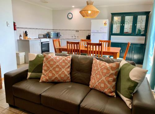 a living room with a brown couch and a kitchen at Wintersun Holiday Cottages in Emu Bay