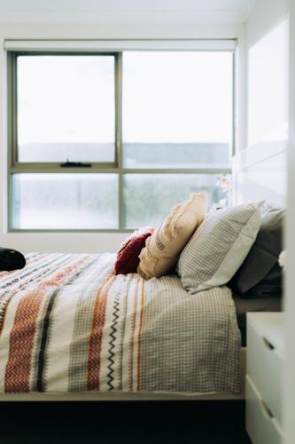 a bedroom with a bed with pillows and a window at 188 Apartments in Perth
