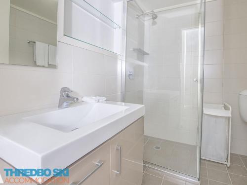 a white bathroom with a sink and a shower at Golden Eagle 1 in Thredbo