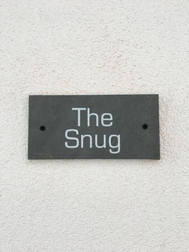 una señal que lee el abrazo en una pared en The Snug- With Private parking en Whitstable