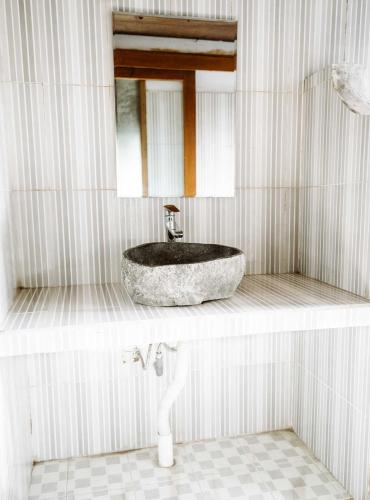 a bathroom with a stone sink and a mirror at Dream CoWork Hotel in Kuta Lombok