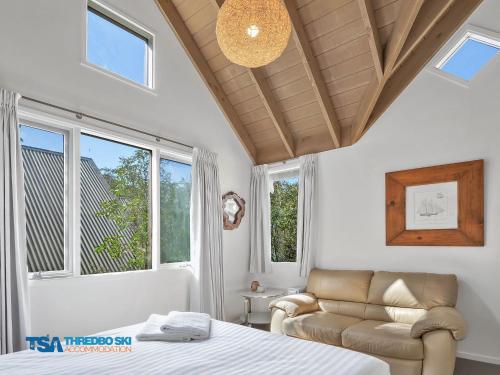 een slaapkamer met een bed, een bank en ramen bij Snowy Chalet in Thredbo