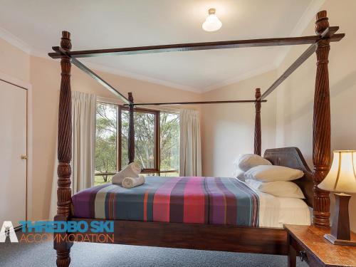 a bedroom with a canopy bed and a window at The Little Nap in Crackenback