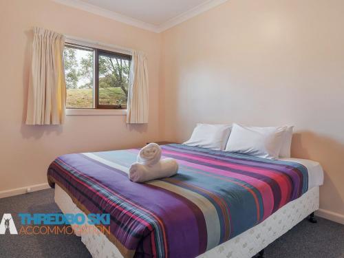 a bedroom with a bed with a teddy bear sitting on it at The Little Nap in Crackenback