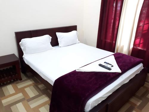 a bedroom with a bed with a remote control on it at Deluxe Residency in Kalpetta
