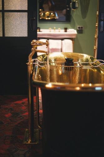 a bathroom with a gold tub with a sink at Stamba Hotel in Tbilisi City