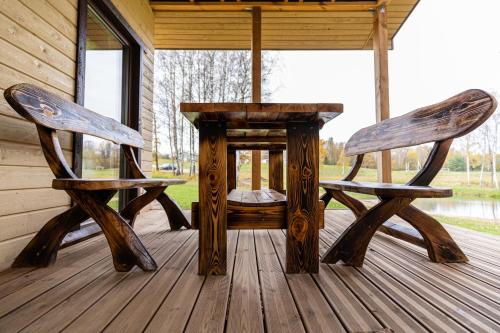 two chairs and a table on the porch of a cabin at Bona Natura Nameliai in Bražuolė