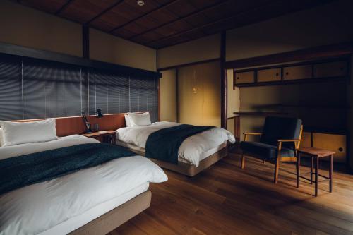 una habitación de hotel con 2 camas y una silla en Tsukihi House Kyoto, en Kioto