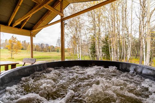 a hot tub filled with water in a gazebo at Bona Natura Nameliai in Bražuolė