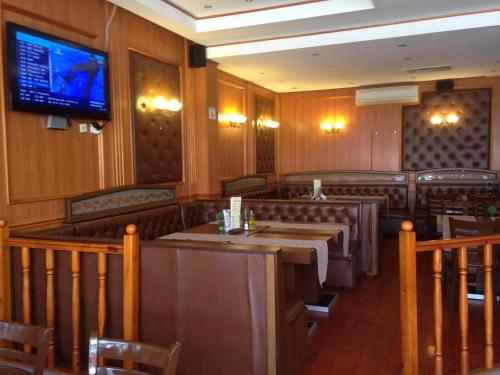 un ristorante con tavoli e sedie e una tv a parete di Hotel Atol a Sunny Beach
