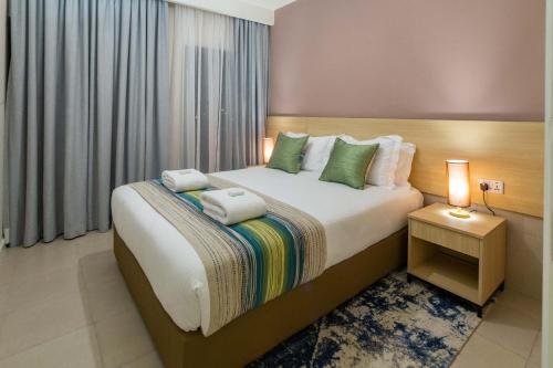 a bedroom with a bed with two towels on it at Kozi Suites Nairobi Airport in Nairobi