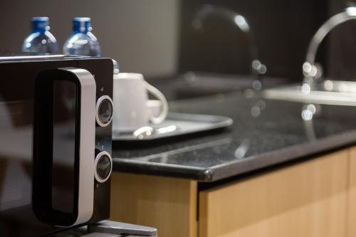 a kitchen counter with a sink and a cup holder at Kozi Suites Nairobi Airport in Nairobi