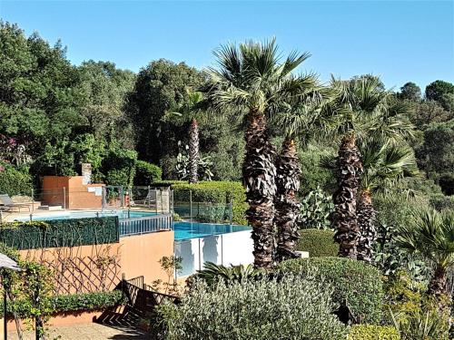 un complexe avec piscine et palmiers dans l'établissement Superbe Duplex 35m2 vue mer avec piscine, à Bormes-les-Mimosas