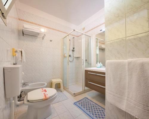 a bathroom with a shower and a toilet and a sink at Hotel Marzia Holiday Queen in Caorle
