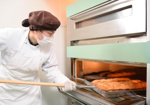 大鰐町にある青森ワイナリーホテル のオーブンから食べ物を取り出すシェフ