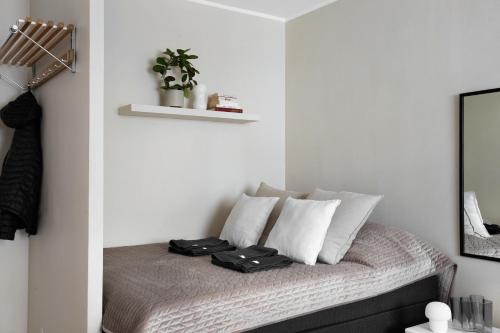 Habitación con cama con almohadas blancas y espejo. en Trendy Nordic Studio by Tram Stop, en Helsinki