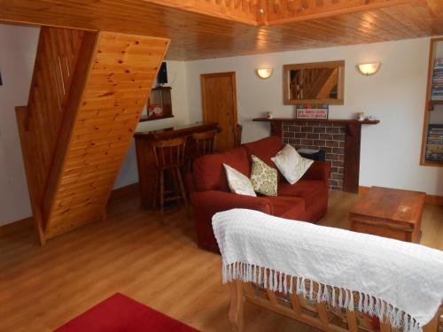 a living room with a red couch and a fireplace at Birchdale Cottage in Rathdrum