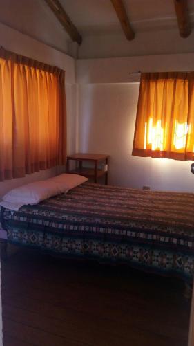 Schlafzimmer mit einem Bett mit orangefarbenen Vorhängen in der Unterkunft Hostal Indigo Urubamba in Urubamba