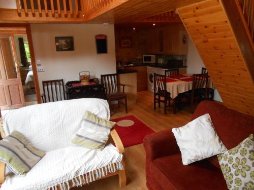 a living room with a white couch and a kitchen at Birchdale Cottage in Rathdrum