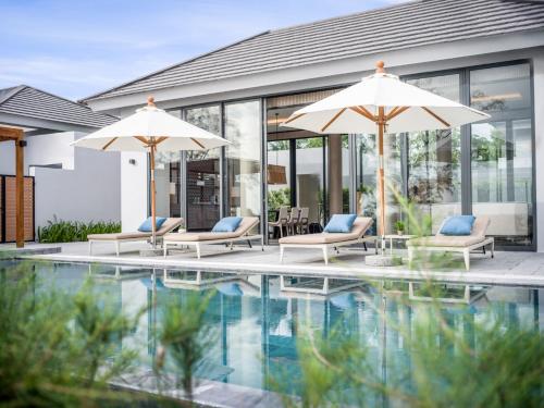a house with a swimming pool with two umbrellas at Crowne Plaza Phu Quoc Starbay by IHG in Phu Quoc