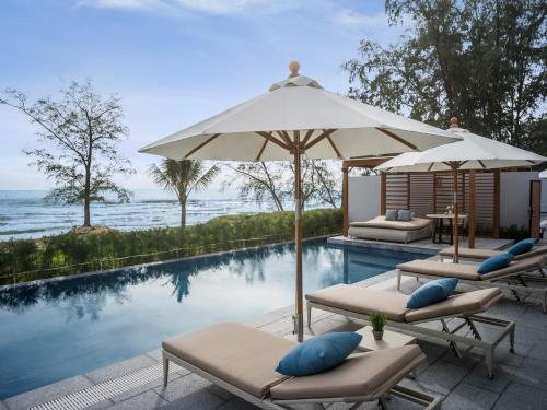 a swimming pool with two lounge chairs and an umbrella at Crowne Plaza Phu Quoc Starbay by IHG in Phu Quoc