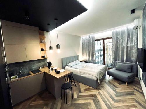 a bedroom with a bed and a desk and a kitchen at Icon Apartaments Drobnera studio in Wrocław
