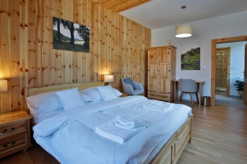 a bedroom with a large white bed with wooden walls at Rezort Gothal Chalupy in Donovaly