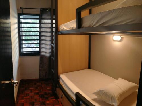 a small room with two bunk beds and a window at Alimama Guesthouse Melaka with Balcony in Melaka