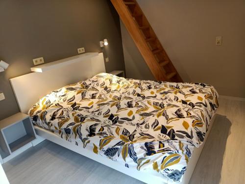 een slaapkamer met een bed met een gele en witte deken bij Les Gites d'Olloy - Le Beauséjour in Olloy-sur-Viroin